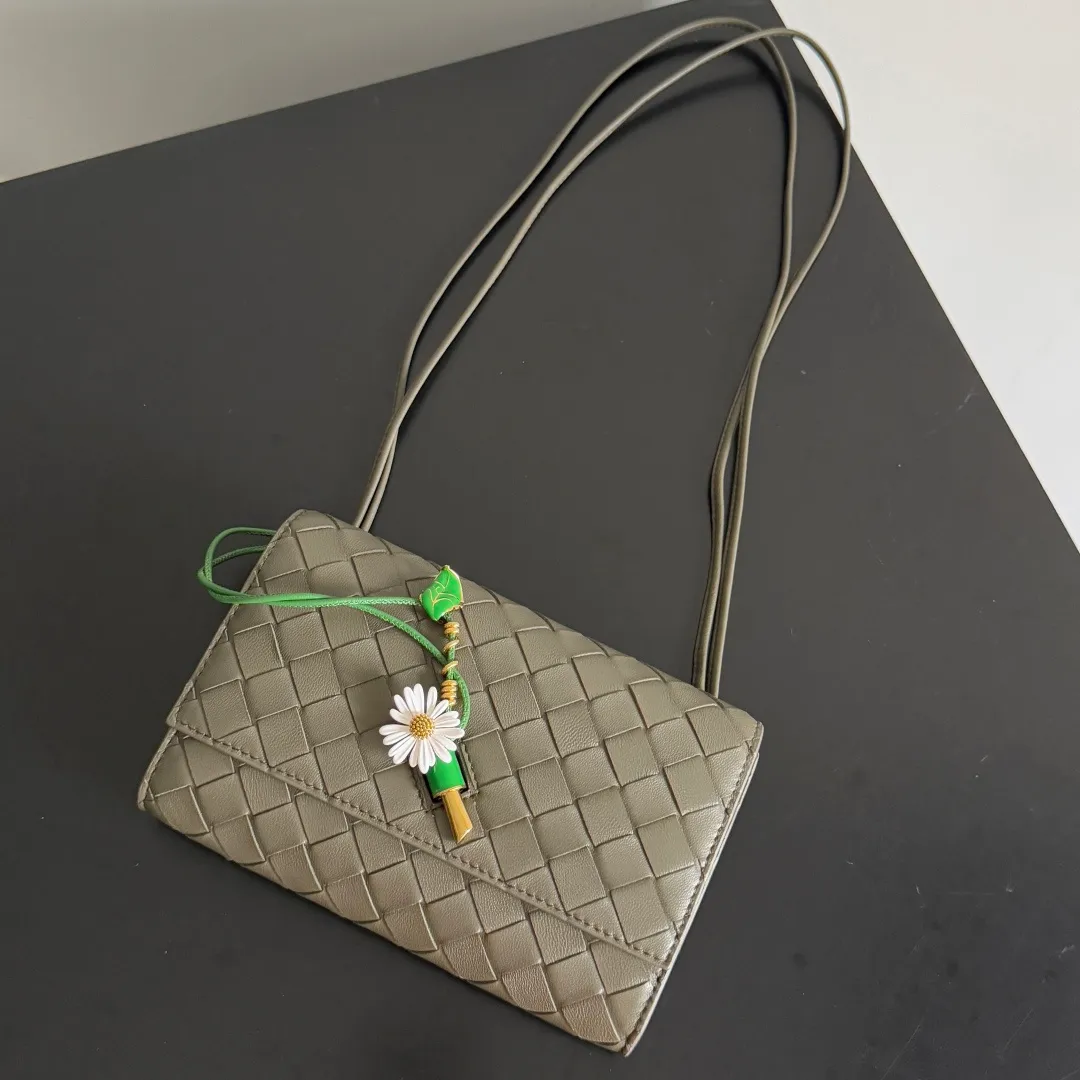 Batch 1560 Bottega Veneta2025 new product Daisy Andiamo bag, classic woven crossbody bag, thin shoulder strap is more casual, especially the small pendant design this time, daisy + green leaves + small gold chain, add a playful and smart look to the tough leather🌼Metallic button and knot closure, simple but not simple, elegant texture, elegant weaving attitude. You can also decide how to carry the bag according to your outfit and occasion. It can be used as a clutch bag, shoulder bag, or crossbody bag. It has a high usage rate. 😊Pair it with a simple skirt to instantly become relaxed and fashionable. Pair it with a smart suit to neutralize the formal feeling. It can be used for commuting and dating! Style number: 838870 (836940) Size: 19*12.6*2cm